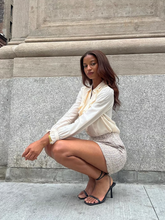 a lady wears a shirt with puff sleeve design and a mini tweed skirt
